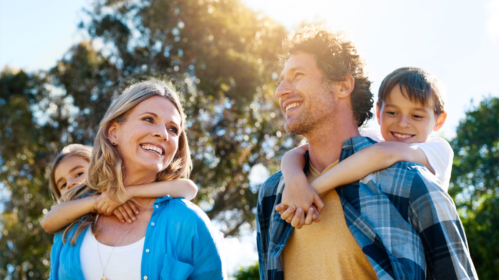 Family walking through park with children on shoulders